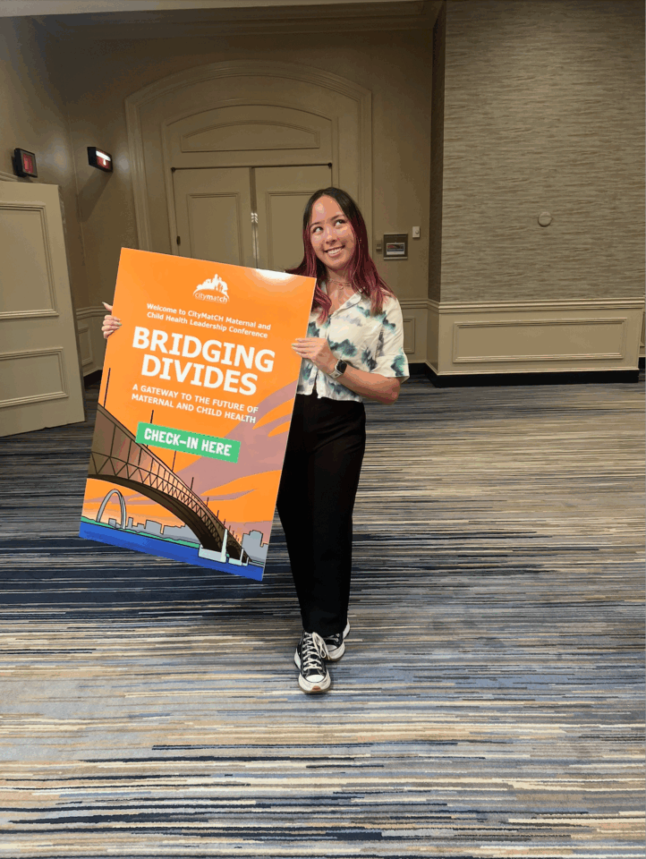 Brina holds an orange welcome sign for CityMatCH